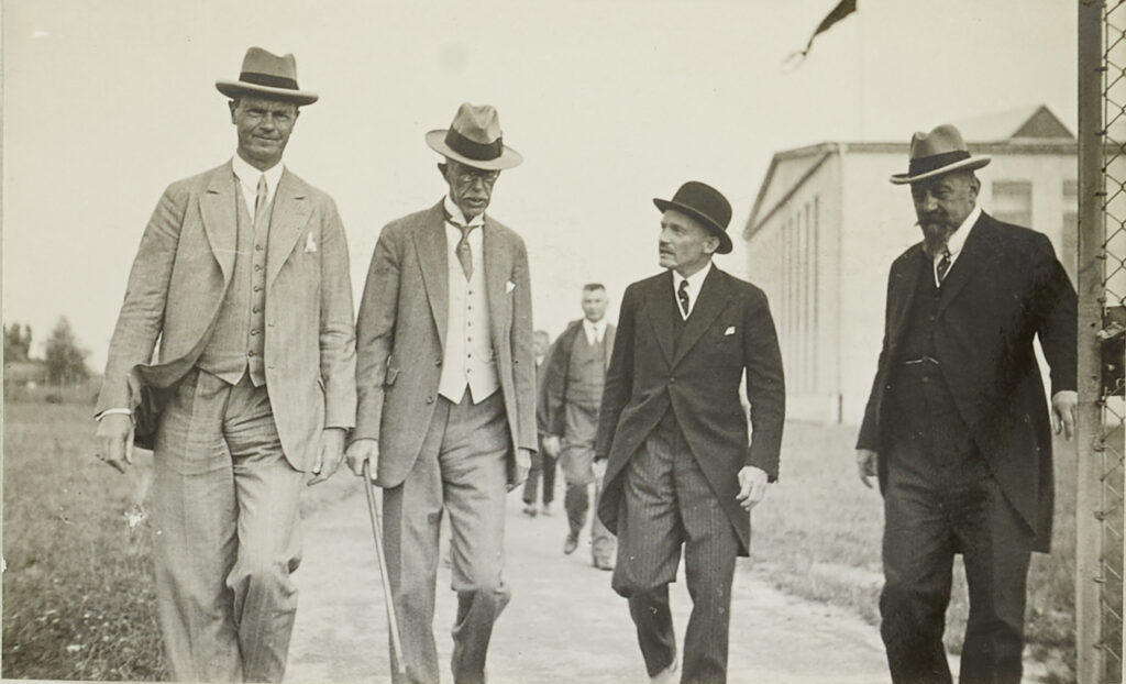 Il piccolo uomo dalla grande visione – qui terzo da sinistra accanto al re Gustavo V di Svezia (1858-1950), alto oltre 1,90 m – mentre lascia il cantiere navale di Altenrhein il 13 agosto 1929. Sigla: Archivio di Stato di San Gallo, W 241/3.00674