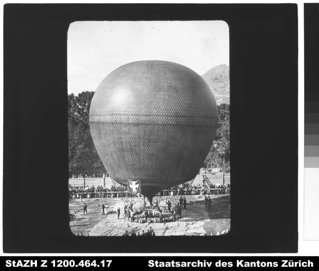 Ballon Wega in Sion am 3. Oktober 1898. Beim Start um 10:53 Uhr betrug die Temperatur 15,3 Grad. Um 11:05 Uhr erreichte die Wega eine Höhe von 2240 m. In 12 Minuten stieg sie um 1700 Höhenmeter. Nach 229 Kilometern landete die Wega um 18 Uhr mit einer Geschwindigkeit von 12,3 m/s in Rivière-les-Fossés in Frankreich. Die maximal erreichte Höhe betrug 6300 m. ü. M. bei minus 22 Grad. Signatur: Staatsarchiv des Kantons Zürich, Schweizer Alpen-Club SAC, Sektion Uto, Z 1200.464.17.