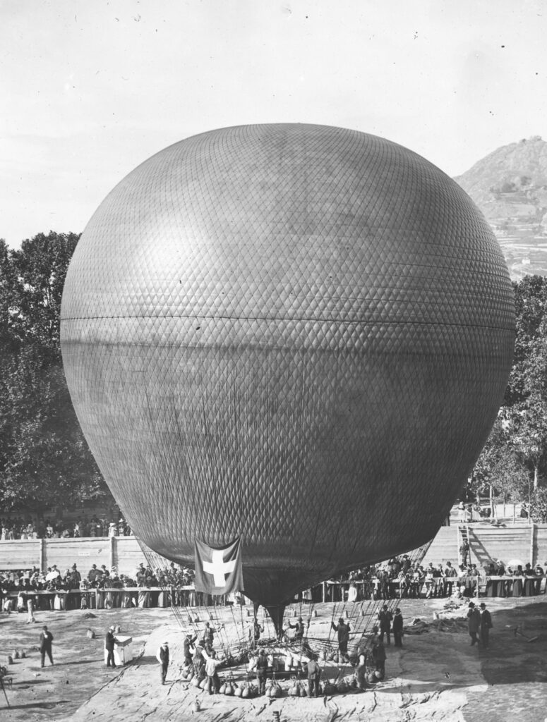 Ballon Wega in Sion am 3. Oktober 1898. Beim Start um 10:53 Uhr betrug die Temperatur 15,3 Grad. Um 11:05 Uhr erreichte die Wega eine Höhe von 2240 m. In 12 Minuten stieg sie um 1700 Höhenmeter. Nach 229 Kilometern landete die Wega um 18 Uhr mit einer Ge- schwindigkeit von 12,3 m/s. Die maximal erreichte Höhe betrug 6300 m. ü. M. bei minus 22 Grad. Signatur: Staatsarchiv des Kantons Zürich, Schweizer Alpen-Club SAC, Sektion Uto, Z 1200.464.17.